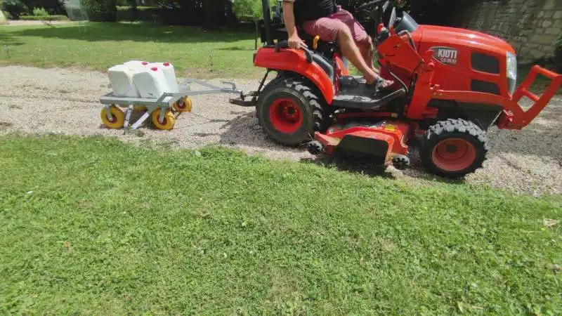 Désherbage mécanique tracté sur cour et allée en gravier par un mini-tracteur